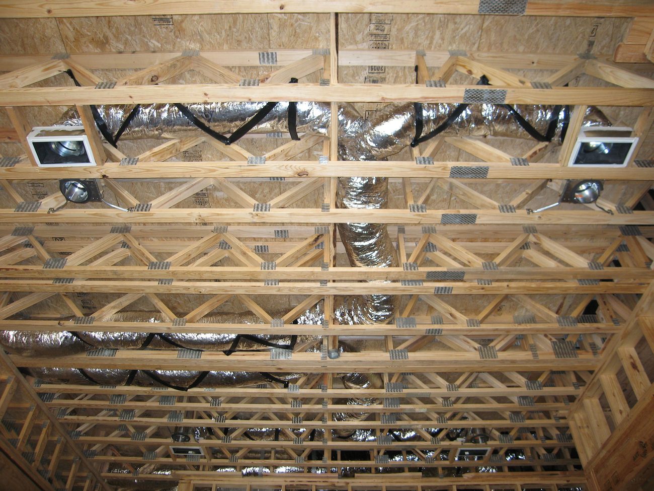Insulated flexible duct routed through floor truss framing, illustrating the physical duct routing addressed when designing an installable HVAC duct system
